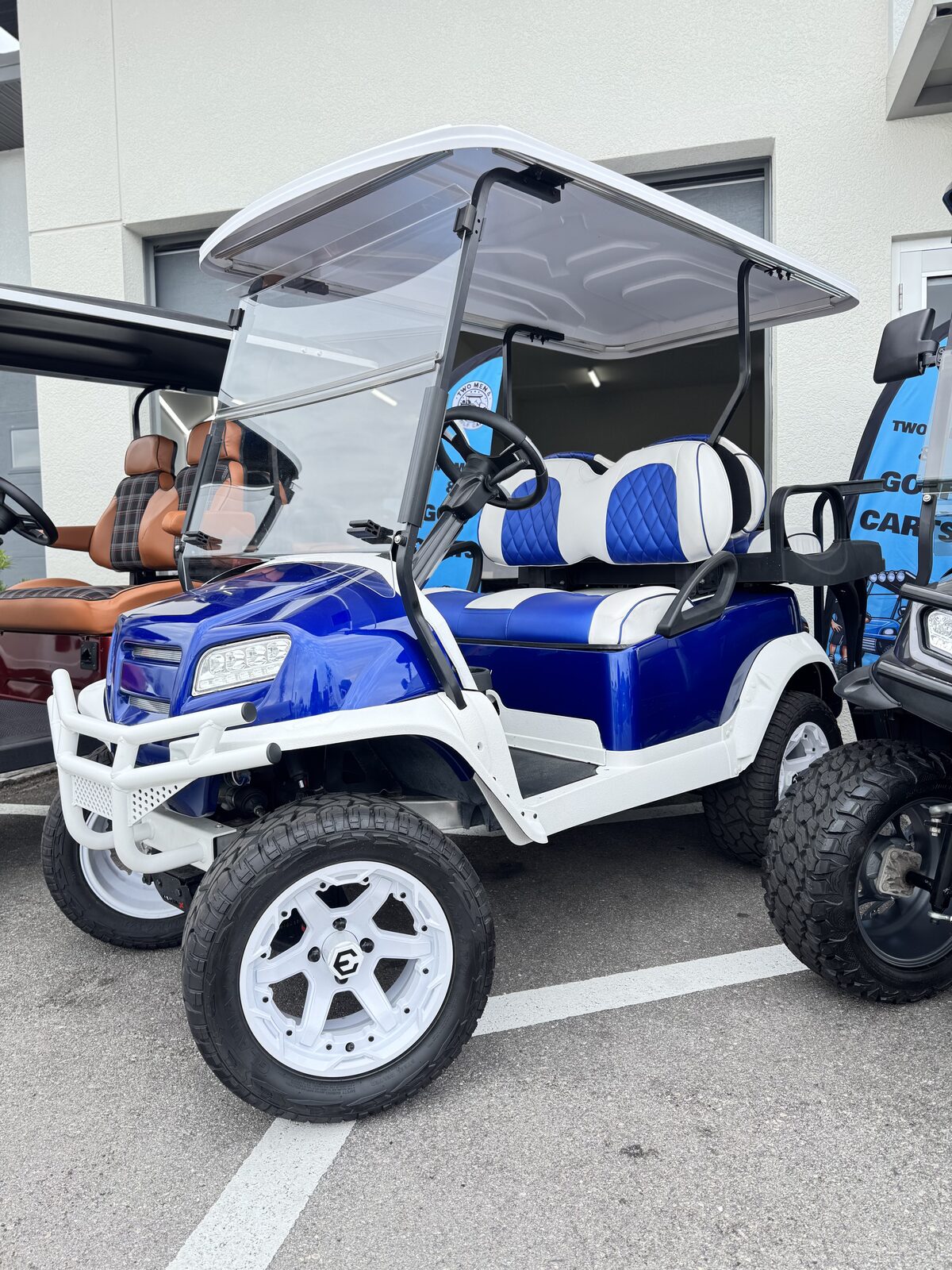 Royal blue lifted Club Car with white brush guard and blue and white diamond stitch seats